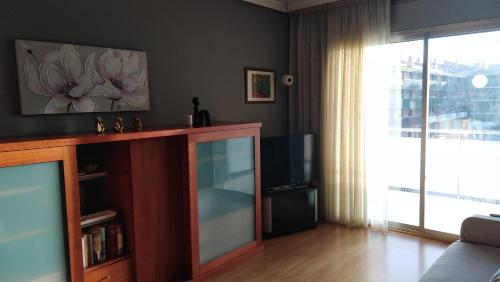 uma sala de estar com televisão e uma grande janela em Apartamento playa Cambrils Torresol 2 em Cambrils