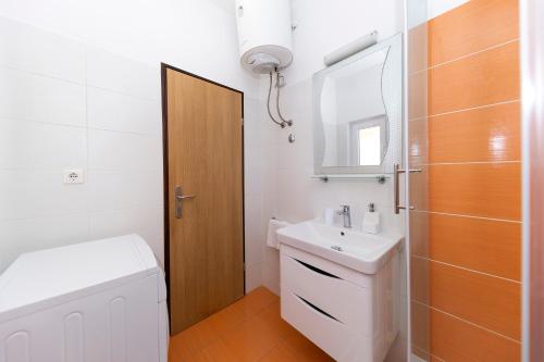 W łazience znajduje się umywalka, toaleta i lustro. w obiekcie Apartmani Valentina w mieście Zadar