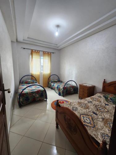 een kamer met 3 bedden en een raam bij Le Coin Appart in Kenitra