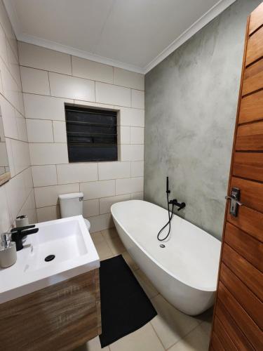 een badkamer met een wit bad en een wastafel bij @Merino in Ermelo