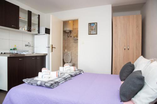 a bedroom with a purple bed and a kitchen at Apartment Silvana in Senj