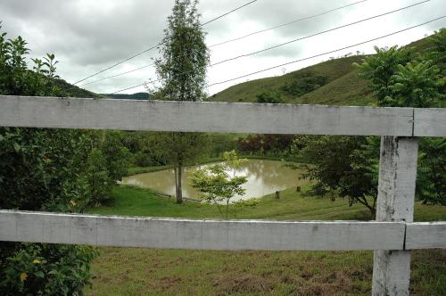 a view of a pond from a wooden fence at Pousada & Camping Serras Verdes in Conservatória