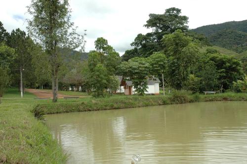 a body of water with a building in the background at Pousada & Camping Serras Verdes in Conservatória