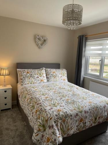 a bedroom with a bed and a window and a chandelier at 32 Maescurig in Newport Pembrokeshire