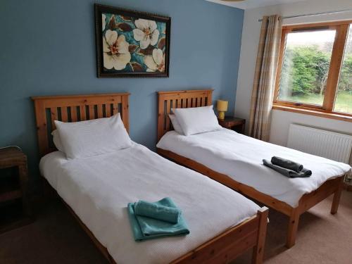 2 letti posti uno accanto all'altro in una camera da letto di Brackenbrae Holiday Cottage ad Acharacle