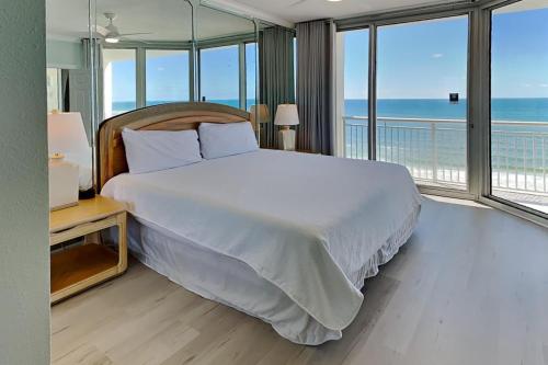a bedroom with a bed and a balcony with the ocean at The Pearl Of Navarre 705 in Navarre