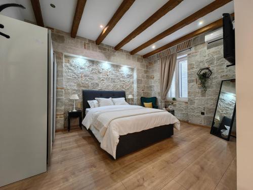 - une chambre avec un grand lit et un mur en pierre dans l'établissement Apartments Lana Spalato, à Split