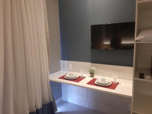 a bathroom with a table with two plates and a tv at Flat Samba Bossa Nova in Cabo Frio