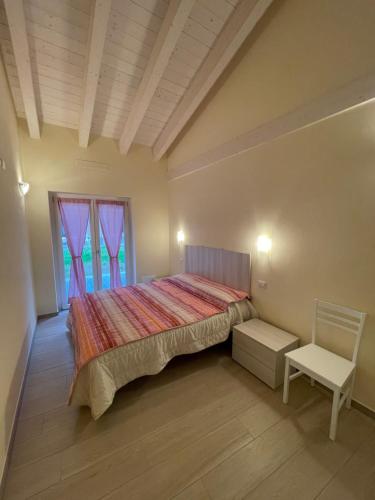a bedroom with a bed and a chair and a window at Casa Tortora in Gravedona