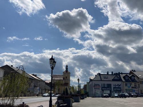 a town with a clock tower and clouds in the sky at Apartament Villa Olivia in Szczebrzeszyn