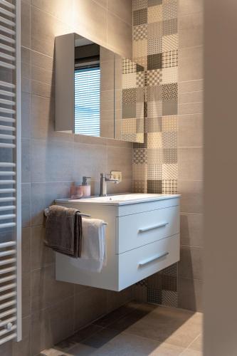 a bathroom with a white sink and a mirror at Vakantiewoning De Bles in Avelgem