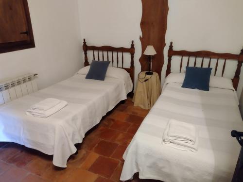 2 camas en una habitación con sábanas blancas y almohadas azules en Cabaña rural la Dehesa 2, en Riópar