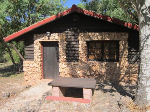 una pequeña casa de piedra con un banco delante en Cabaña rural la Dehesa 2, en Riópar