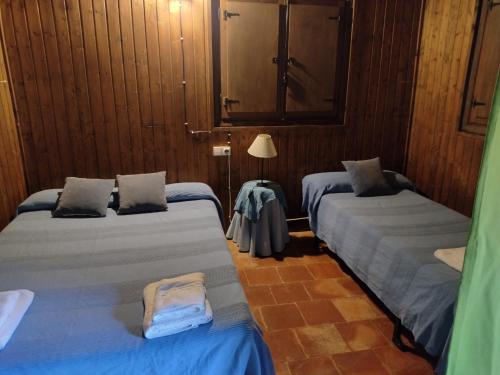2 camas en una habitación con paredes de madera en Cabaña rural la Dehesa 2, en Riópar