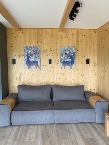 a couch in a living room with wooden walls at WALDHAUS HIRSCH Bungalow only for you self check in in Pörtschach am Wörthersee