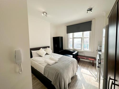 a white bedroom with a bed and a window at the upper floor in Croydon