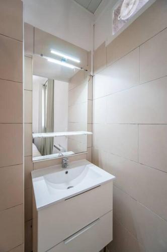 une salle de bain blanche avec un lavabo et un miroir dans l'établissement Appartement tout équipé balcon 4 pers St Charles, à Marseille