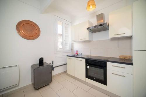 a kitchen with white cabinets and a black appliance at Appartement tout équipé balcon 4 pers St Charles in Marseille