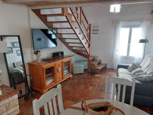 ein Wohnzimmer mit einer Treppe und einem TV in der Unterkunft Maison typique oléronaise in Le Château-dʼOléron