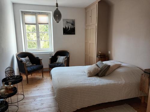 une chambre avec un lit et deux chaises et une fenêtre dans l'établissement Le Kesbel entre Strasbourg et Colmar en centre Alsace, à Lièpvre