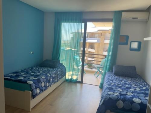 1 Schlafzimmer mit 2 Betten und einem Balkon in der Unterkunft COOSY APPARTEMENT PRESTIGIA PLAGE DES NATIONS in Sidi Bouqnadel