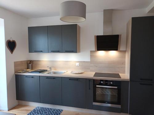 - une cuisine avec des placards bleus, un évier et une cuisinière dans l'établissement Le Kesbel entre Strasbourg et Colmar en centre Alsace, à Lièpvre