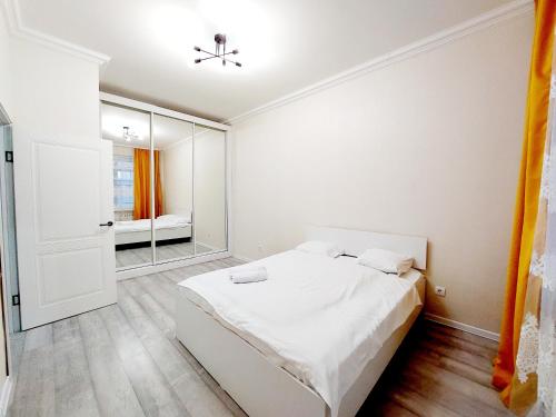 a white bedroom with a bed and a mirror at ЖК Сапфир центр столицы in Taldykolʼ