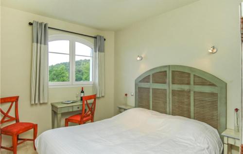 een slaapkamer met een bed en 2 stoelen en een bureau bij 2 Bedroom Amazing Apartment In Callian in Callian