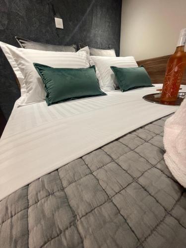 a large white bed with green pillows on it at Maestrale 315° Apartments in Néa Michanióna