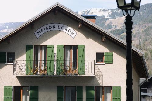 a building with green doors and a balcony at Hôtel Maison Doron in Beaufort