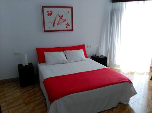 a bedroom with a red and white bed and a window at ANTIC ESTANC in Campanet