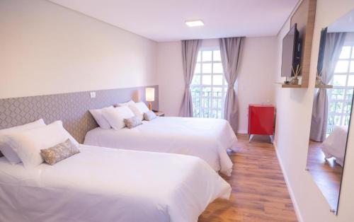 a hotel room with two beds with white sheets at Village de Charme - 2km do Capivari in Campos do Jordão