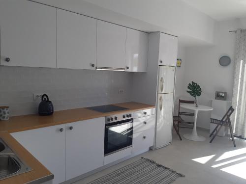 a kitchen with white cabinets and a white refrigerator at Sea Breeze Apartment in Ixia