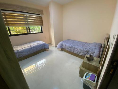 Habitación pequeña con 2 camas y ventana en Moon Apartments, en Jerash