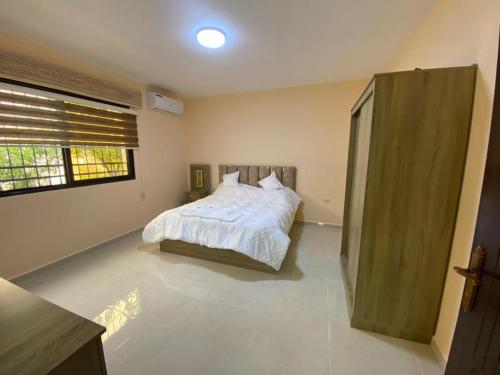 a bedroom with a white bed and a window at Moon Apartments in Jerash