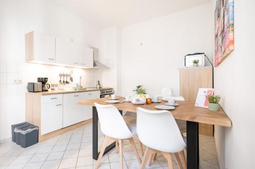 a kitchen with a wooden table and white chairs at Apartments an der Oper - Innenstadt - Zentral - Küche - Wifi - Powered by Ko-Living in Halle an der Saale