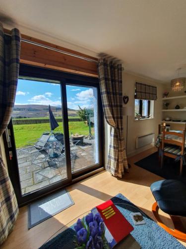a living room with a large sliding glass door at Self catering accommodation three bedroom house or one bedroom cottage in Tomintoul