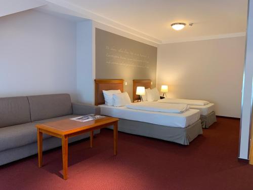 a hotel room with two beds and a couch at Batschari Palais Baden-Baden in Baden-Baden