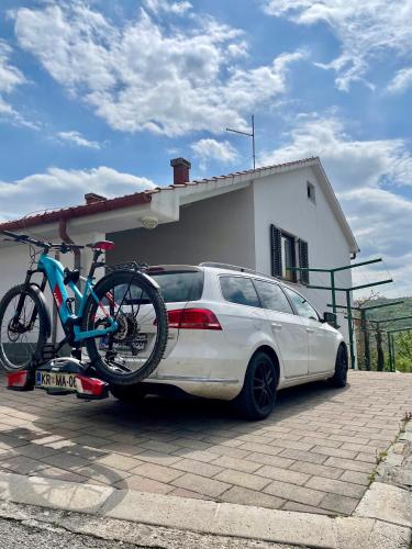 a bike on the back of a car parked in front of a house at Olea Mar apartma in Pobegi