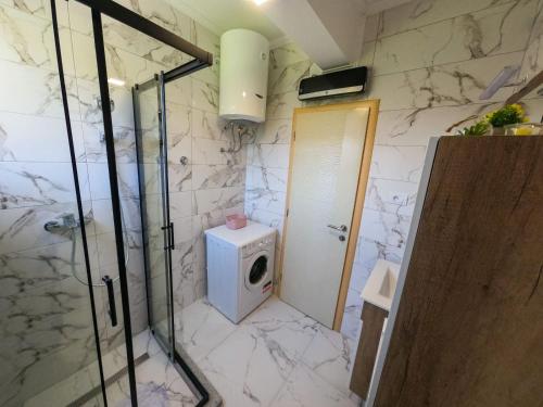 a bathroom with a shower and a washing machine at Apartman KOSTA in Trebinje