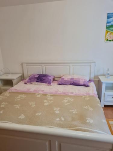 a bed with purple and pink pillows on it at Apartment Bataja in Brkač