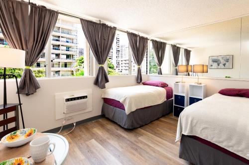 ein Hotelzimmer mit 2 Betten und einem Tisch in der Unterkunft soulfactory Hawaii in Honolulu