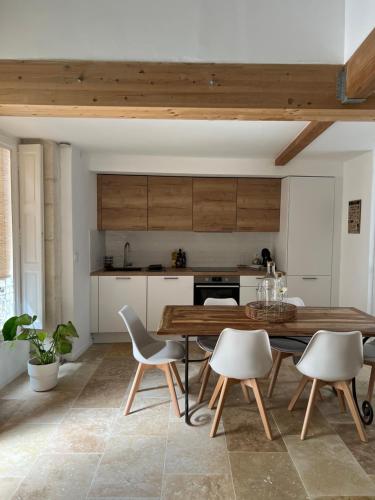 une cuisine avec une table et des chaises en bois dans l'établissement L'escapade Nîmoise, à Nîmes