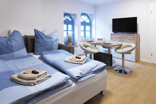 a room with two beds and a table and a television at Pension "Zum Reußischen Hof" in Thallwitz