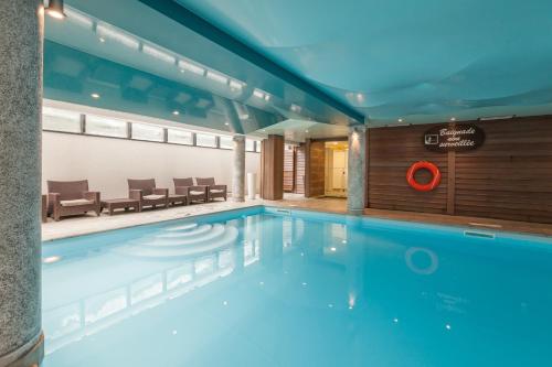 - une piscine d'eau bleue dans un bâtiment dans l'établissement Résidence Pierre & Vacances Premium La Ginabelle, à Chamonix-Mont-Blanc