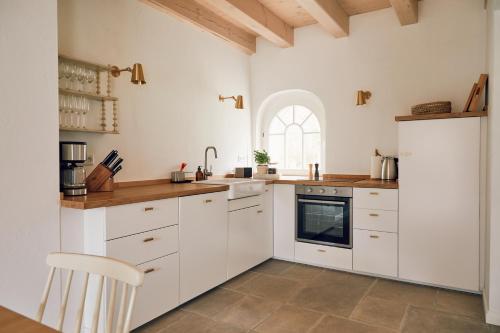 a white kitchen with white cabinets and a window at Wäscherei in Barkelsby