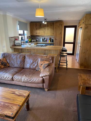 a living room with a brown couch and a kitchen at Spacious 10 bed house in Leicester in Leicester
