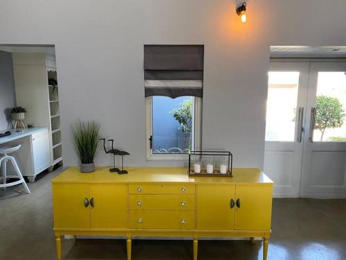 a yellow dresser in a living room with a window at Dam'n Devine in Parys