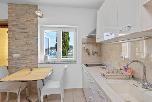 a kitchen with white cabinets and a table and a window at Apartments Čikat Mali Lošinj in Mali Lošinj