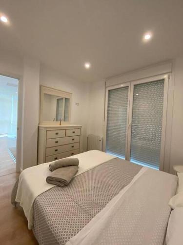 um quarto branco com uma cama, uma cómoda e uma janela em Chalet en Aldán em Cangas de Morrazo